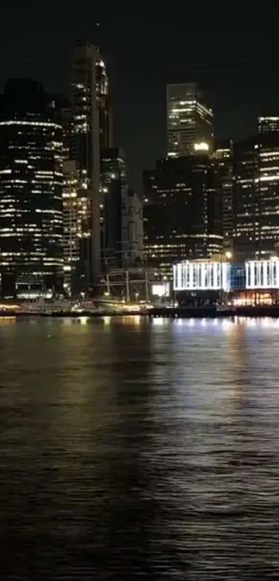 Night cityscape with illuminated skyscrapers and reflective water.