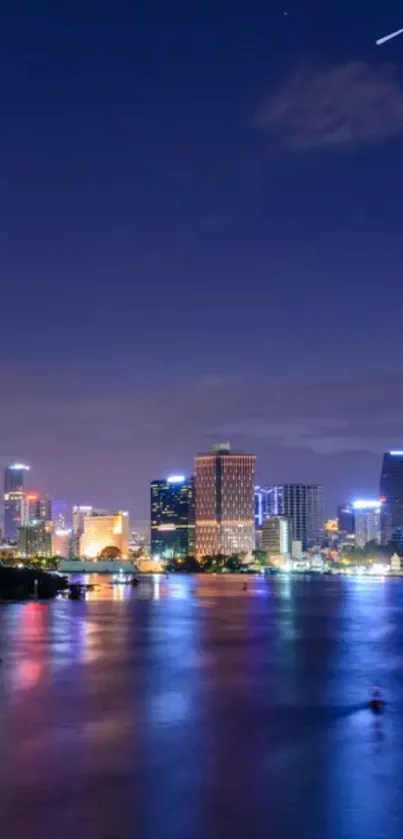 Cityscape at night with river reflections and a starry sky.