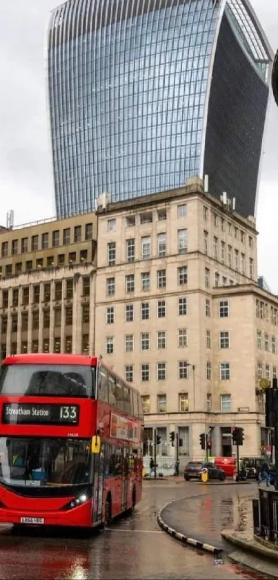 Red London bus on a rainy street with modern skyscrapers.