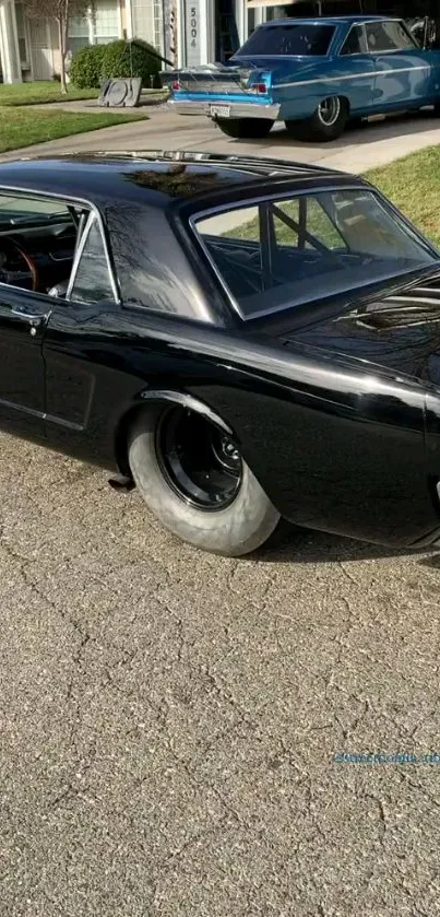 Mobile wallpaper of a classic black muscle car parked in a driveway.