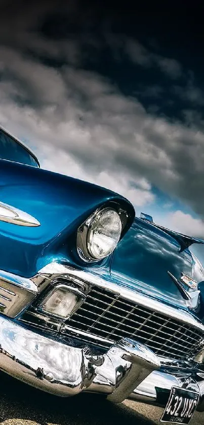 Close-up of a classic blue car with chrome details under a cloudy sky.