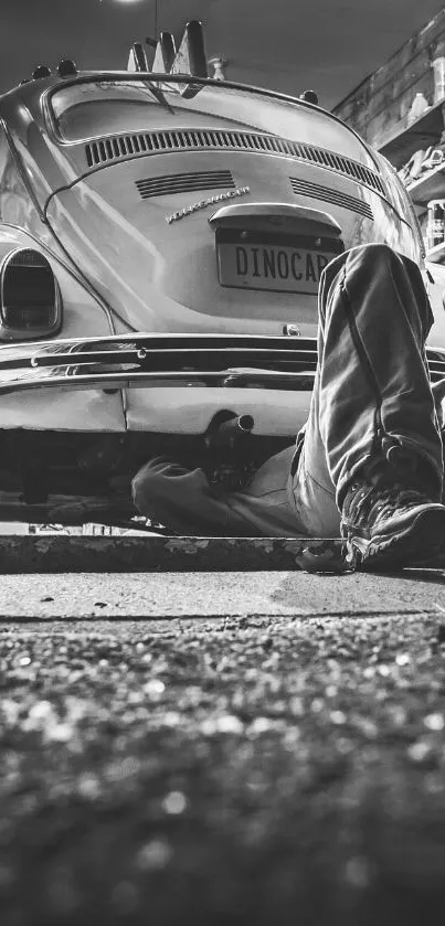 Black and white image of a mechanic working on a classic car in a garage.