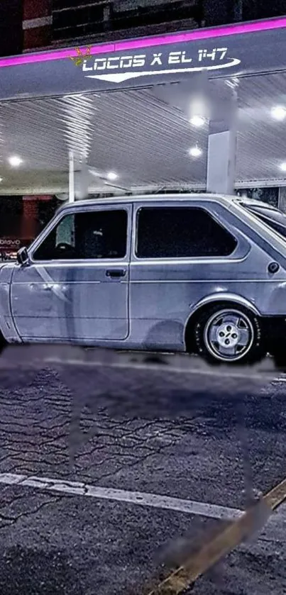 Classic car parked under a lit gas station canopy at night.