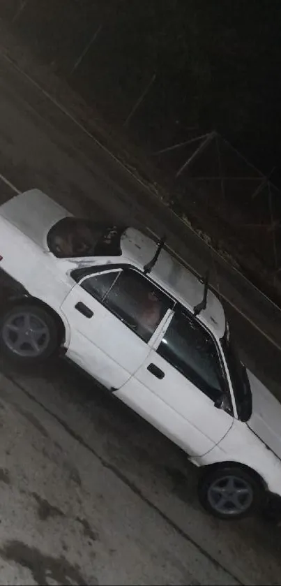 A classic white car driving on a wet road at night, showcasing vintage charm.