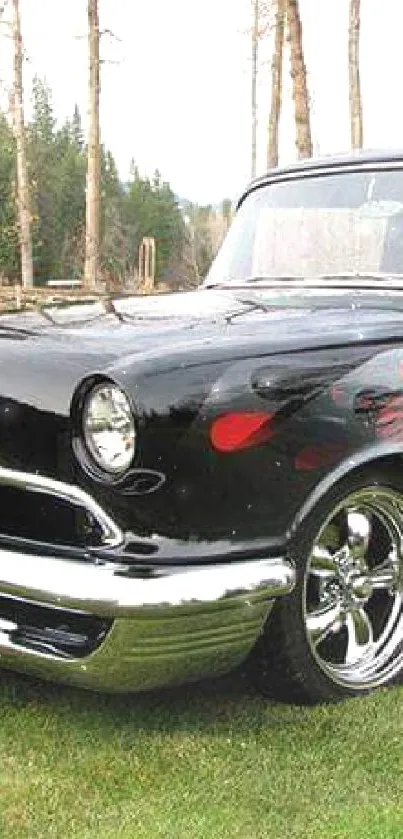 Classic black and red car with flame design on green grass.