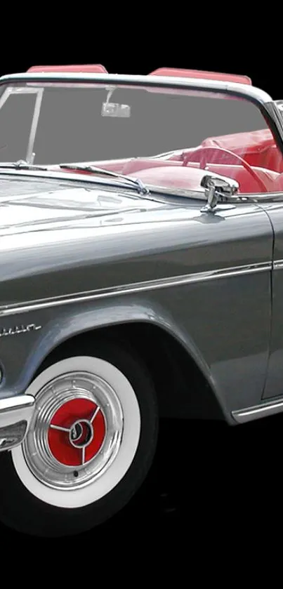 Vintage convertible car with red interior and sleek design on a black background.