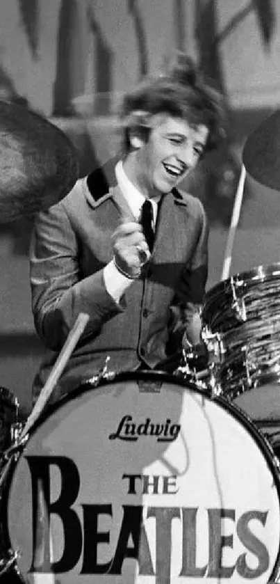 Vintage black and white drummer playing on stage with iconic band logo.