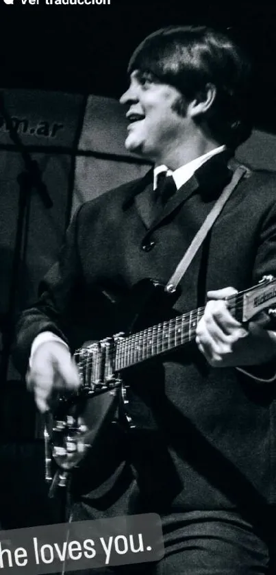 Black and white photo of a guitarist holding a guitar on stage.