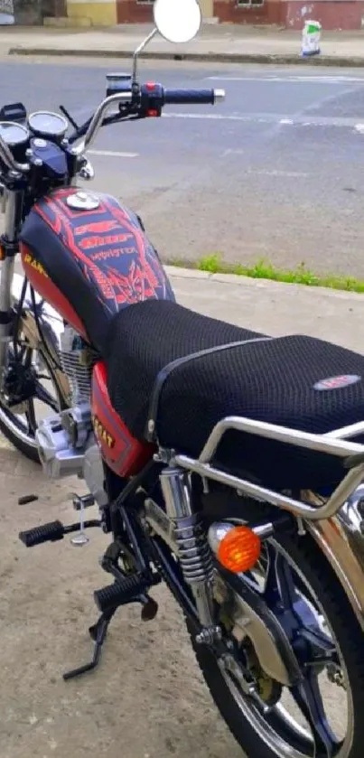 Classic motorcycle with red and black design parked on roadside.