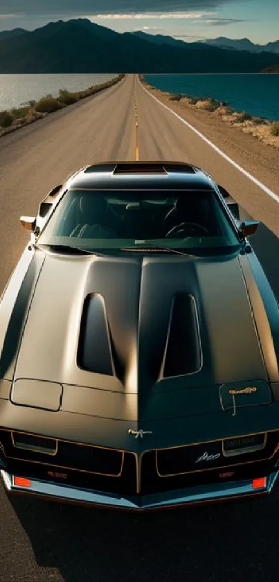 Classic muscle car on scenic mountain road with lake view wallpaper.