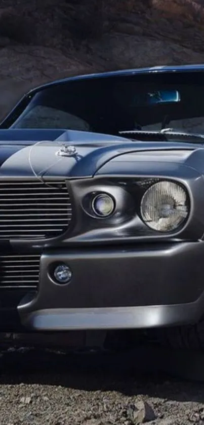 Sleek classic muscle car in dark gray on rocky terrain.