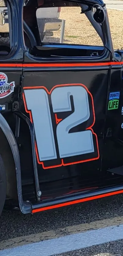 Vintage racing car with number 12, black and orange design in the foreground.