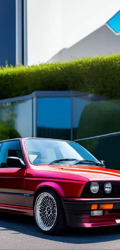 Classic red BMW E30 parked stylishly against a modern backdrop.