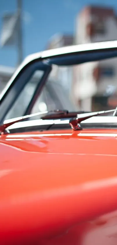 Vibrant red classic car wallpaper with urban scene.