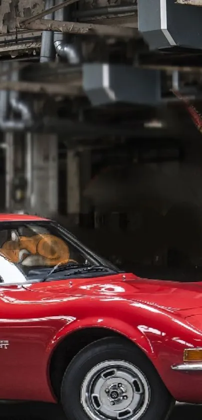 Vintage red car parked in an industrial setting, perfect wallpaper for car enthusiasts.