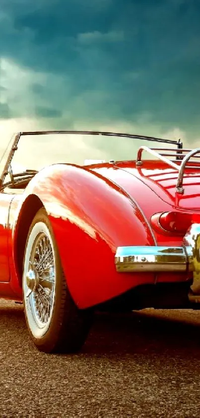 Red vintage convertible car at sunset on open road.