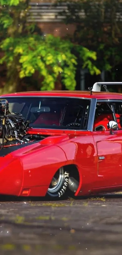 Vibrant red muscle car with engine exposed set against green background.