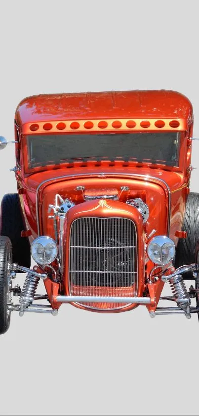 Red vintage car with chrome parts on gray background.