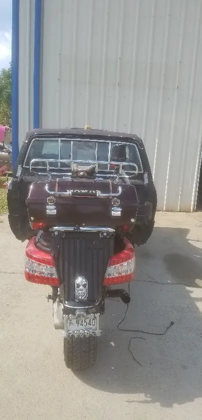 A vintage scooter parked in front of a white garage building.