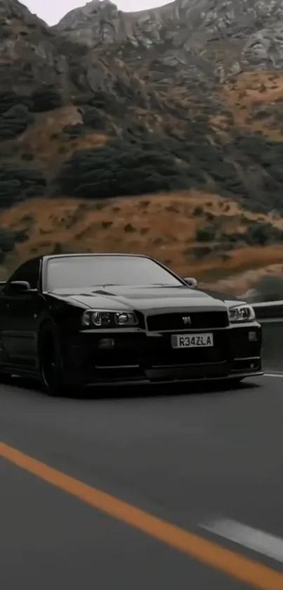 Black sports car driving on a scenic mountain road.