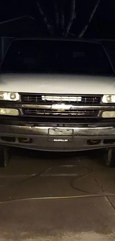 Classic truck at night with glowing headlights.