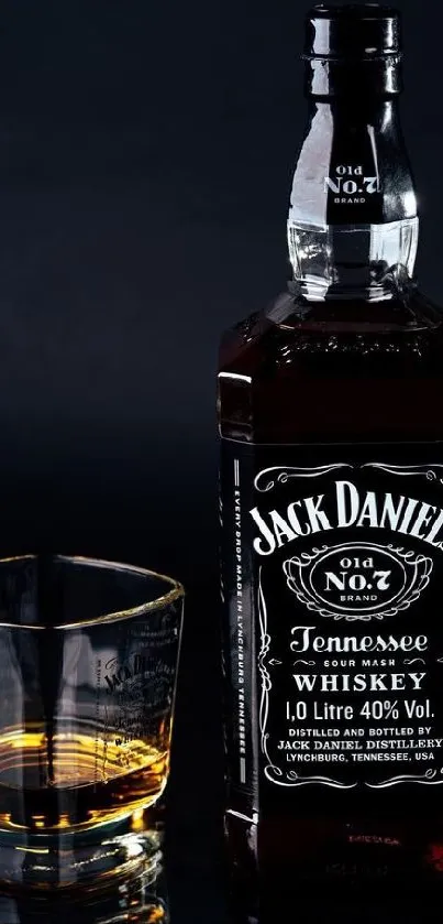 Whiskey bottle with glass on dark background.