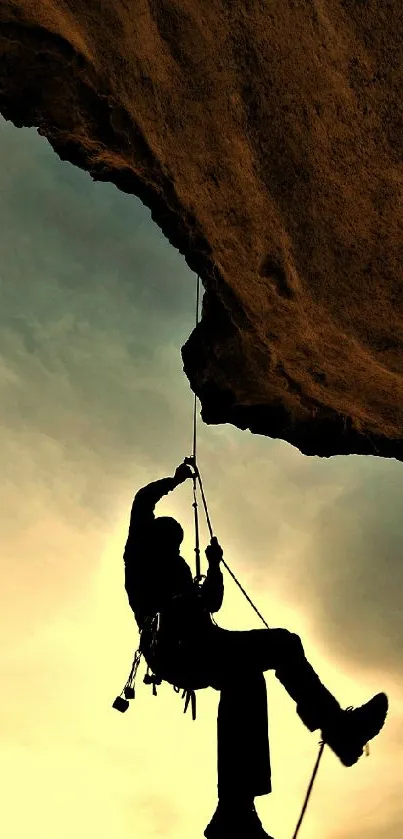 Silhouette of a rock climber against a golden sunset background.