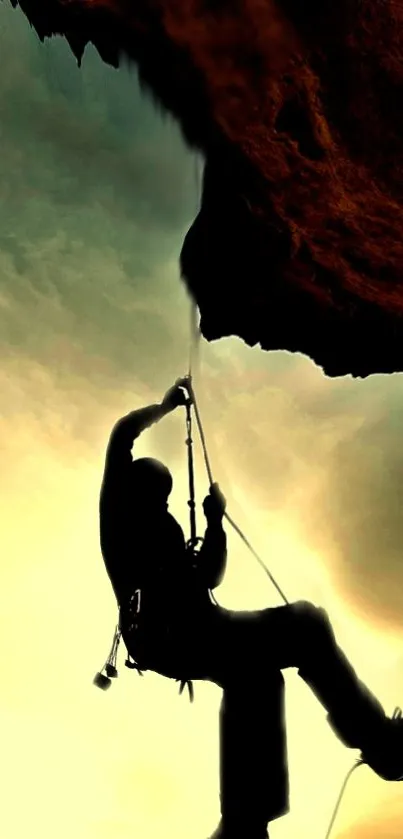 Silhouette of a climber ascending a rock against a golden sky.