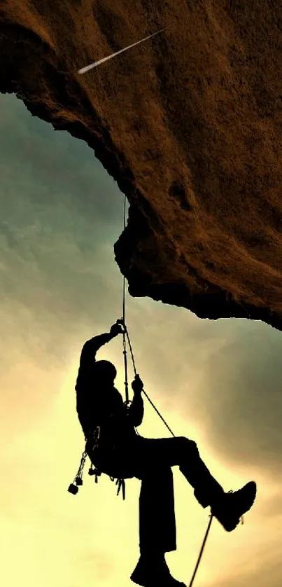 Silhouette of a climber hanging against a warm sunset sky.