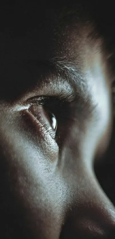 Close-up photo of a human eye in profile with dark, moody tones.