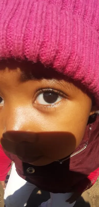 Close-up of a child wearing a pink beanie, looking intently at the camera.