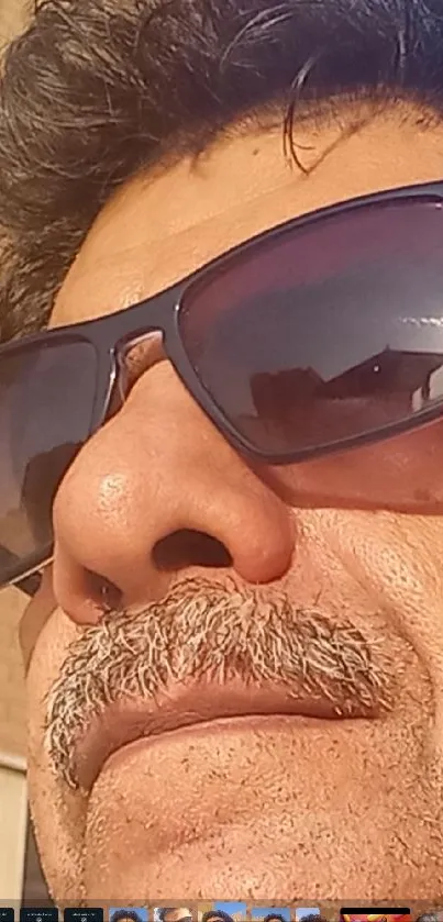 Close-up of a man wearing sunglasses reflecting an urban scene.