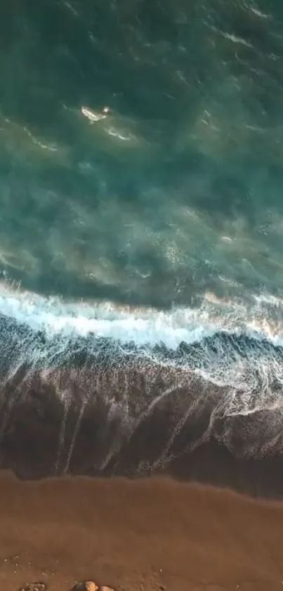 Aerial view of waves crashing on a sandy beach with turquoise water.