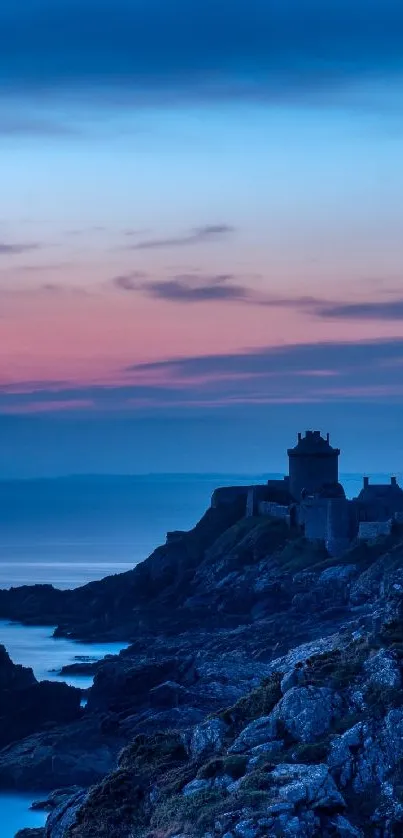 Castle silhouette against a pink and blue sunset sky by the coast.