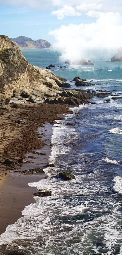 Seaside cliff with ocean waves and a sandy beach under a blue sky.