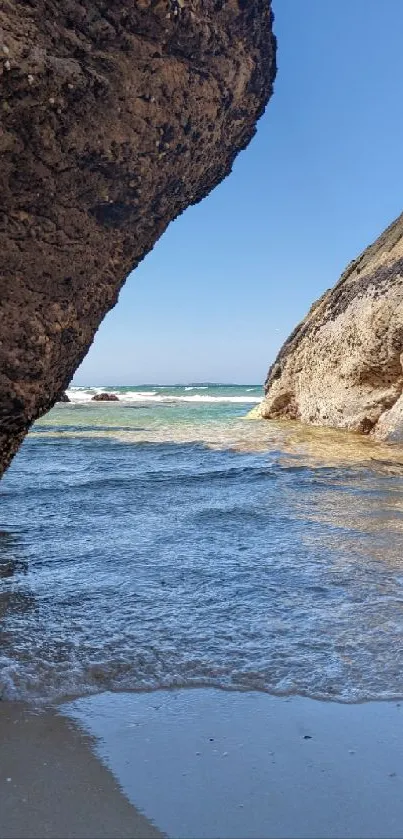 Scenic view of ocean framed by rocky cliffs under a bright blue sky.