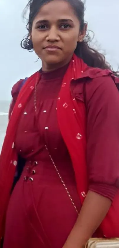 Woman in maroon by the ocean, serene autumn vibes.