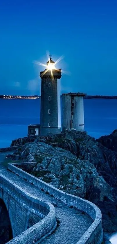 Lighthouse on rocky coast under a deep blue evening sky.