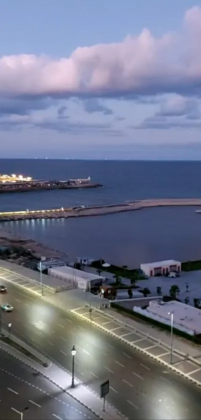 Coastal city at night with illuminated streets and ocean in view.