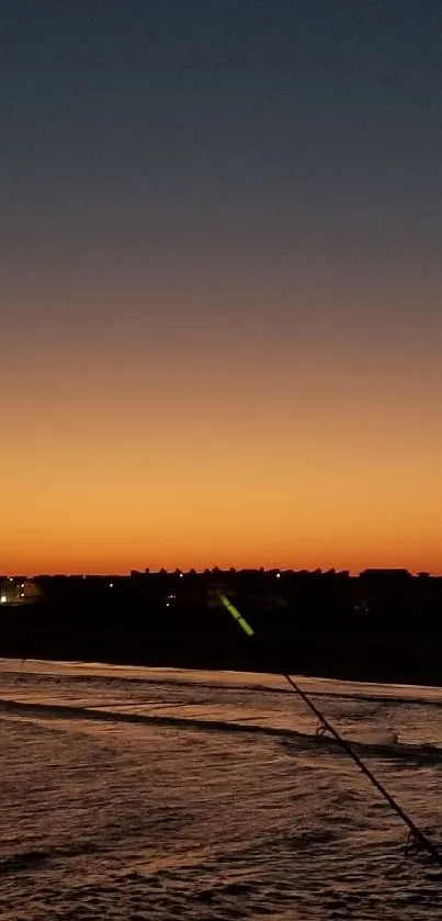 Coastal sunset skyline over ocean and city silhouette.