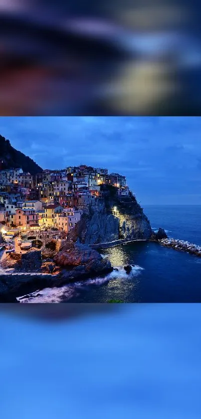 Night view of a lit coastal village by the sea with vibrant blue hues.