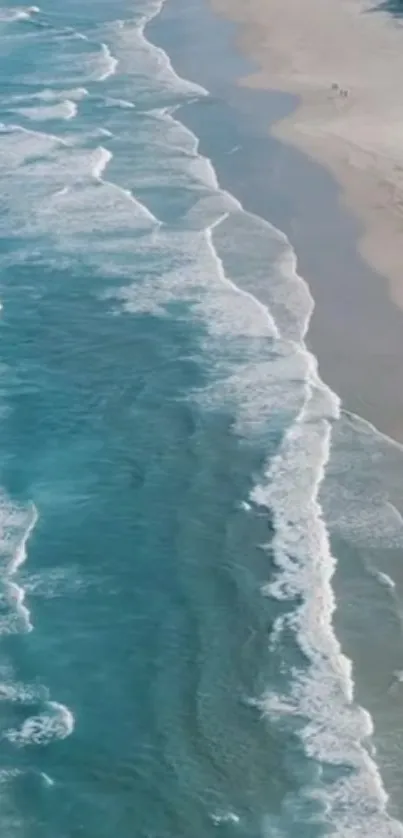 Aerial view of turquoise ocean waves meeting a sandy beach.