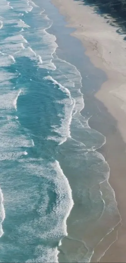 Aerial view of ocean waves and sandy beach, serene coastal scene.