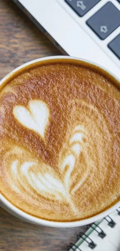 Heart-shaped latte art beside a laptop.