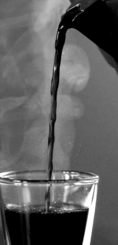 Black coffee pouring into a clear glass cup with steam rising.