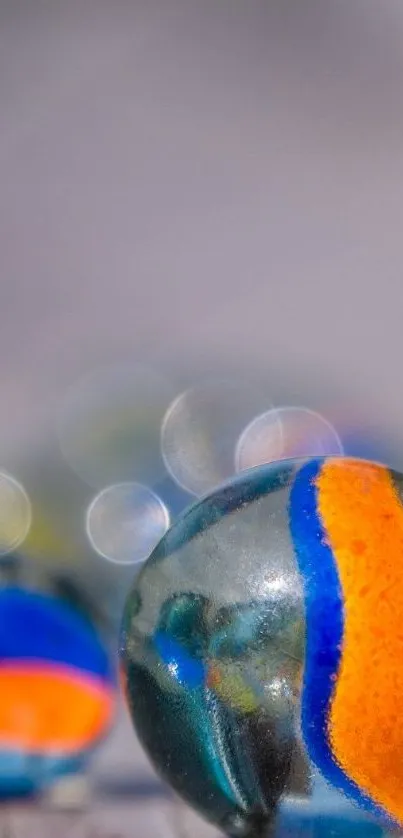 Close-up image of colorful marbles with orange and blue patterns on a light gray background.