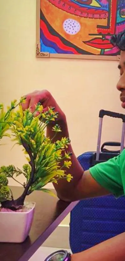 Young person with plant and colorful art on the wall.