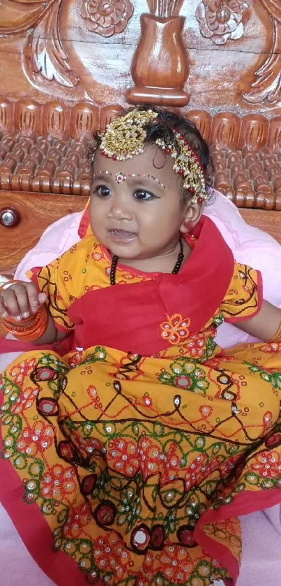 Baby in vibrant traditional Indian attire with intricate patterns.