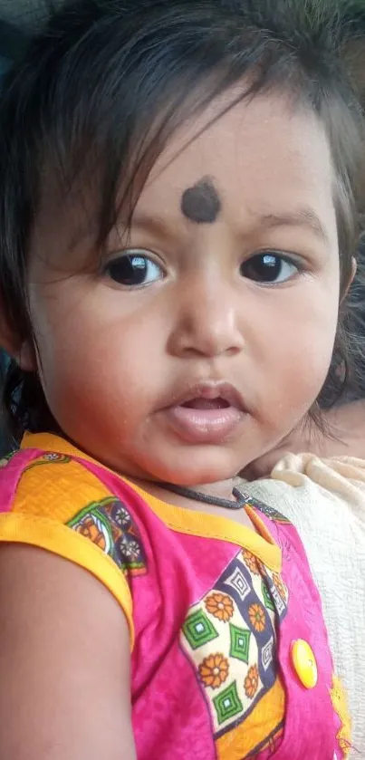 Cute baby in colorful outfit with pink and orange highlights.