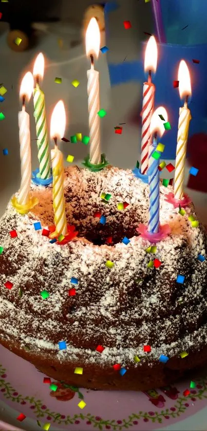 Colorful birthday cake with lit candles on a decorated plate.
